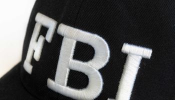 Close up of the FBI logo on a black cap. The text stands for...