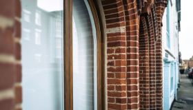 Shallow focus of an arched brick pillar located of the outside of commercial offices down a narrow street.