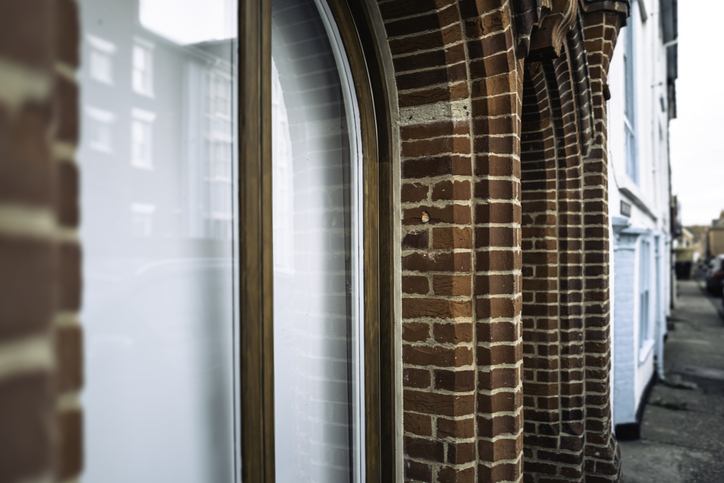 Shallow focus of an arched brick pillar located of the outside of commercial offices down a narrow street.